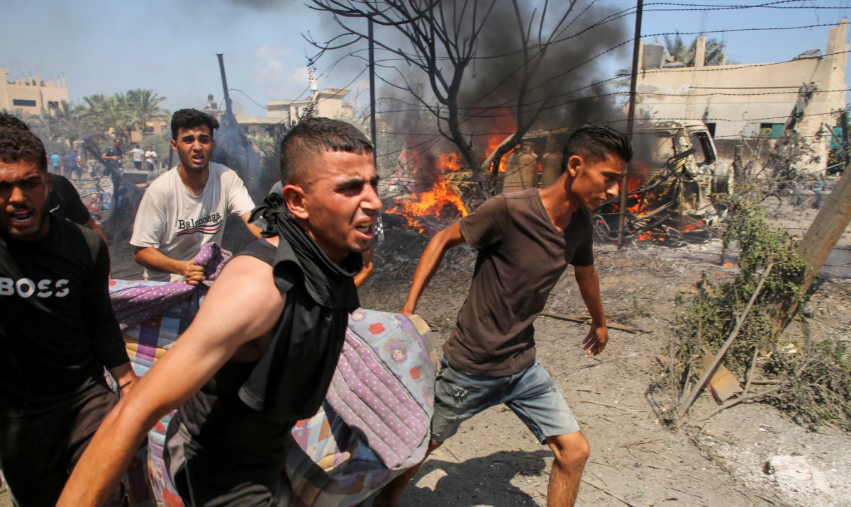 People carry a casualty at the site of what Palestinians say was an Israeli strike at a tent camp in Al-Mawasi area, amid Israel-Hamas conflict, in Khan Younis in the southern Gaza Strip July 13, 2024. (Reuters)