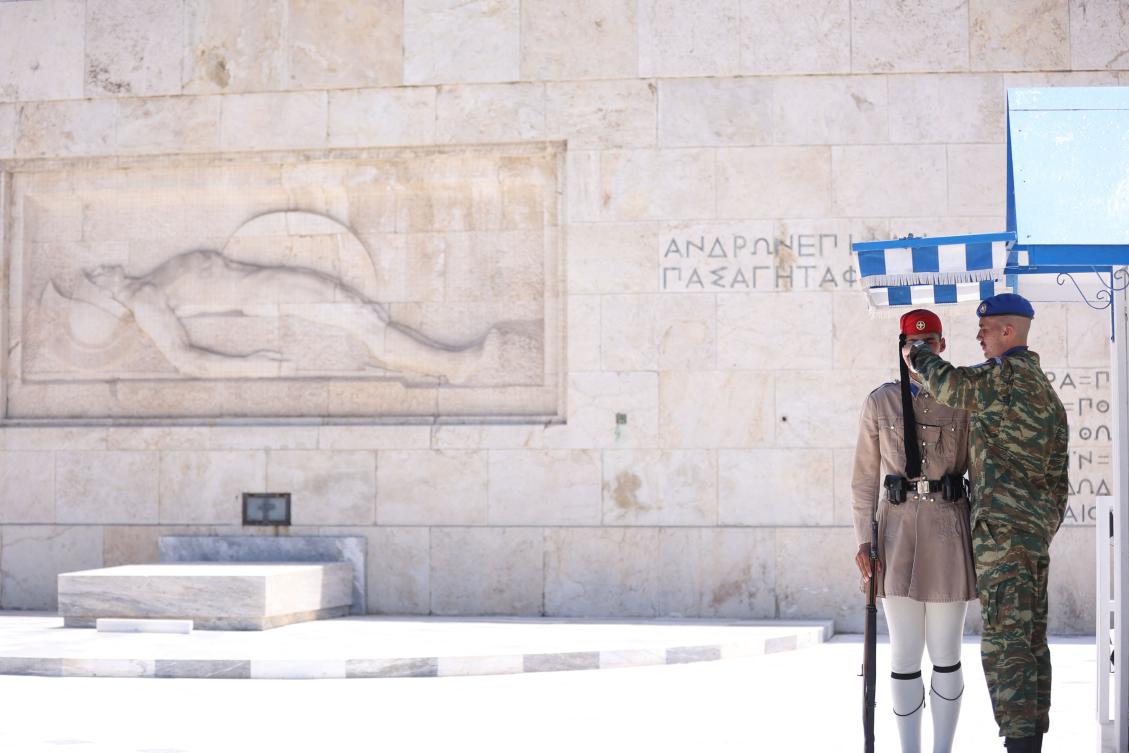 An officer gives water to a presidential guard member standing in front of the monument of The Unknown Soldier in Syntagma Square in Athens on July 12, 2024. (AFP)