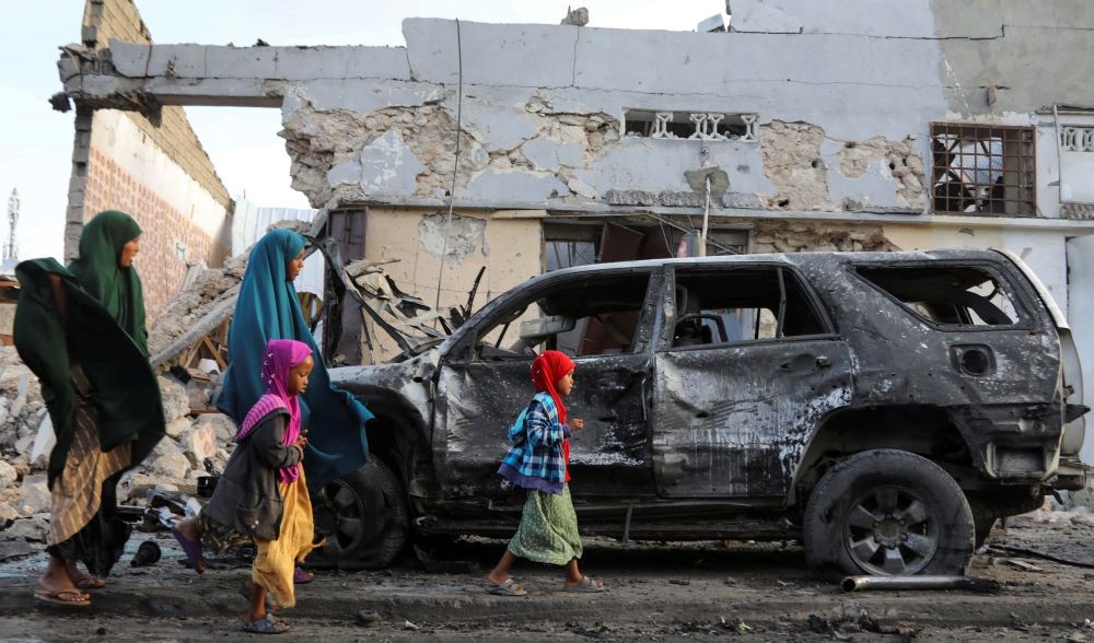 Somalis walk past the wreckage of a vehicle at the scene of an explosion outside a restaurant where patrons were watching the final of Euro 2024 on TV, Mogadishu, Somalia, July 15, 2024. (Reuters)