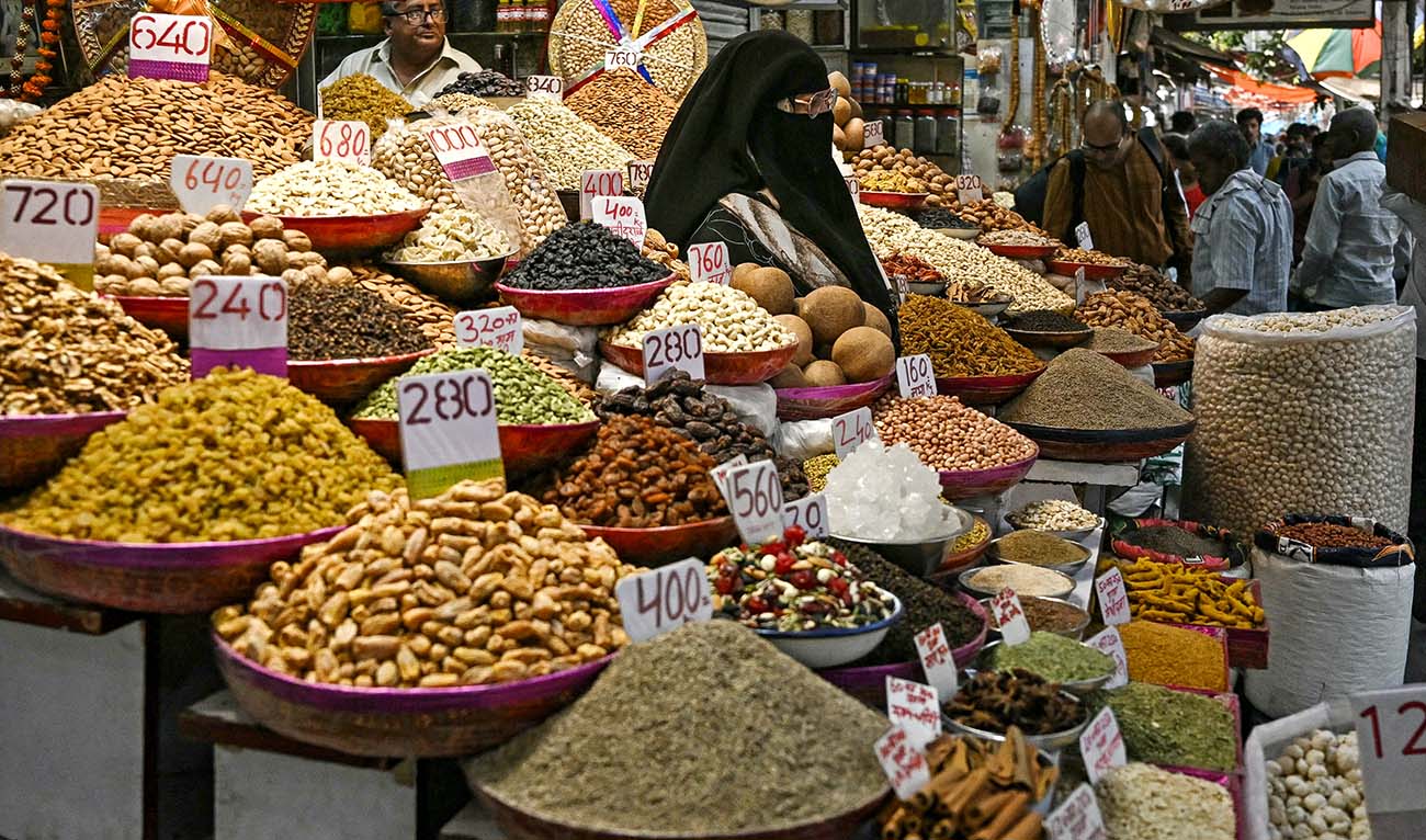 A burqa-clad woman checks on spices at a wholesale spice market in old quarters of Delhi on May 21, 2024. (AFP/File)