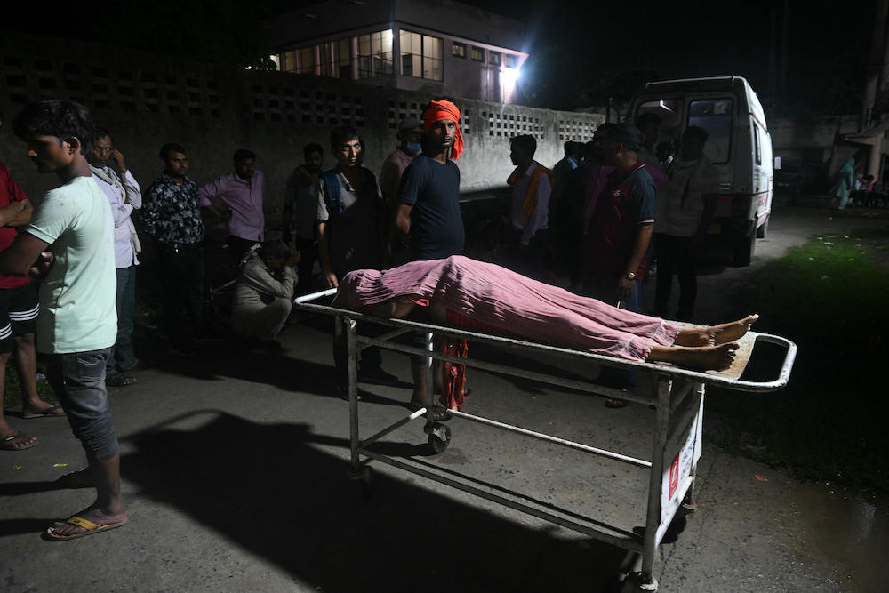 Relatives gather around the body of a victim, who died in a stampede following a sermon delivered by police constable-turned-preacher Bhole Baba in the northern city of Hathras on July 2, 2024. (AFP)