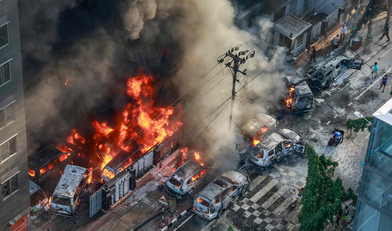 Smoke rises from the burning vehicles after protesters set them on fire near the Disaster Management Directorate office, during the ongoing anti-quota protest in Dhaka on July 18, 2024. (FP)