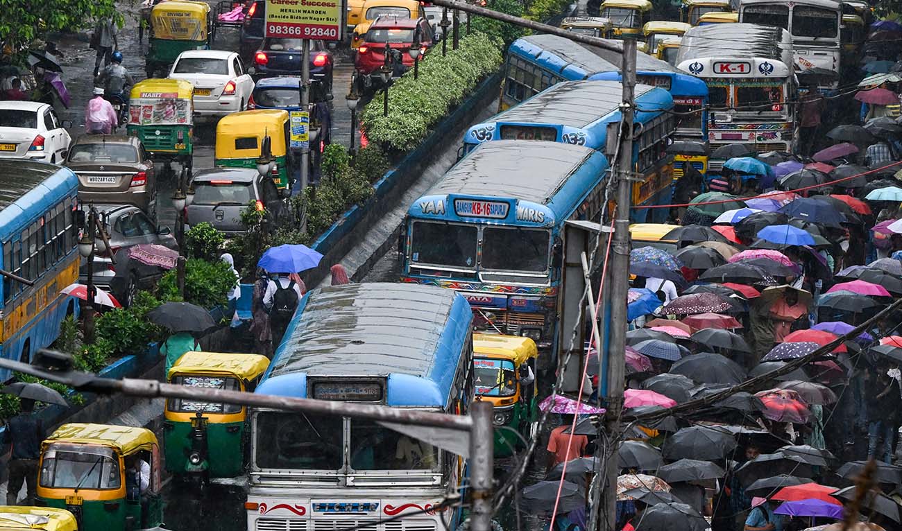 Commuters make their way amid rainfall in Kolkata on July 12, 2024. (AFP)