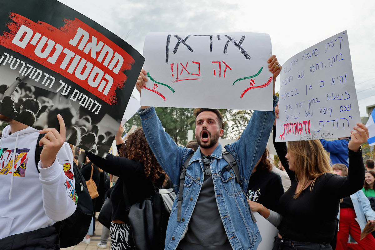 Israeli students hold a sign reading in Hebrew "We are in Iran", during a demonstration against Prime Minister Benjamin Netanyahu's new hard-right government, in Tel Aviv University's campus. (File/AFP)