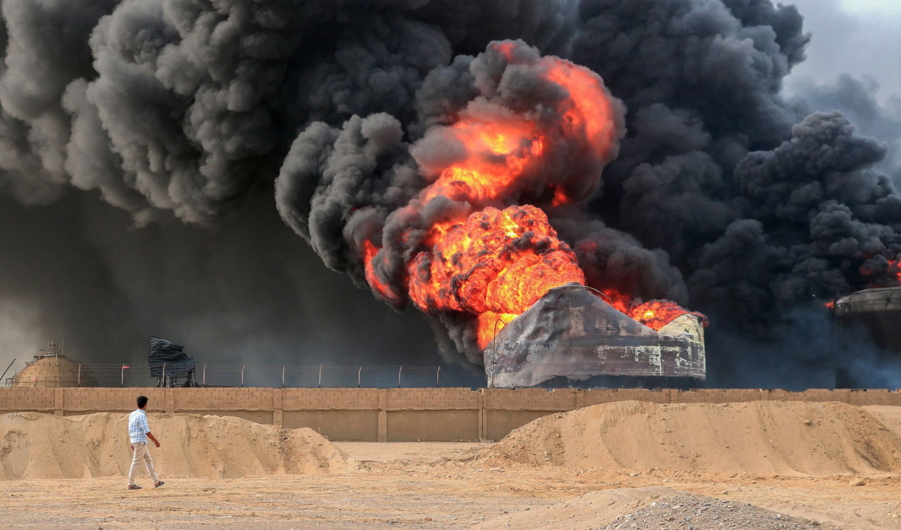 A man walks across from a raging fire at oil storage tanks a day after Israeli strikes on the port of Yemen’s Houthi-held city of Hodeida on July 21, 2024. Yemen’s Houthi rebels on July 21 promised a “huge” retaliation against Israel following a deadly strike on the port of Hodeida, as regional fallout widens from months of war in Gaza. (AFP)