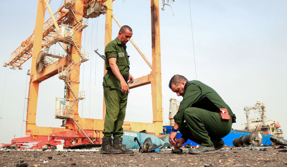 Members of security forces inspect the debris littering a loading dock a day after Israeli strikes on the port of Yemen's Huthi-held city of Hodeidah on July 21, 2024. (AFP)