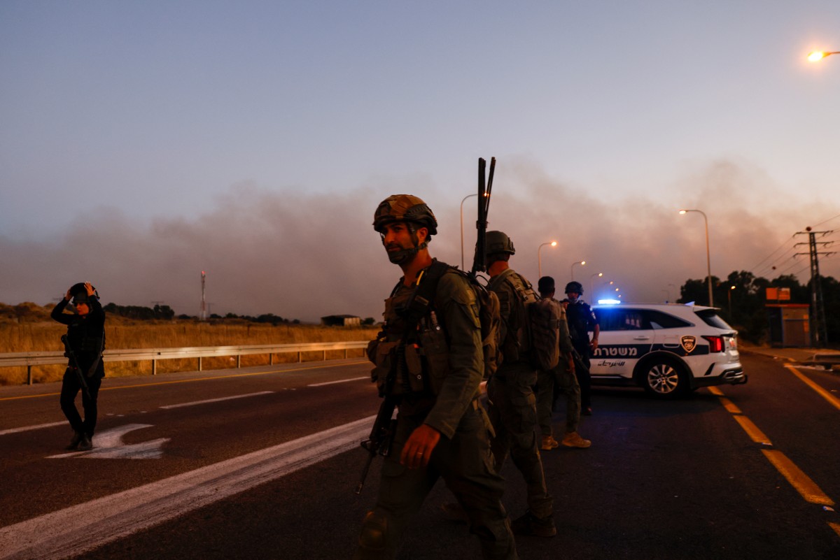 Israeli soldiers and police secure a road as rockets are launched from southern Lebanon in the Israeli-annexed Golan Heights on July 9, 2024. (AFP)