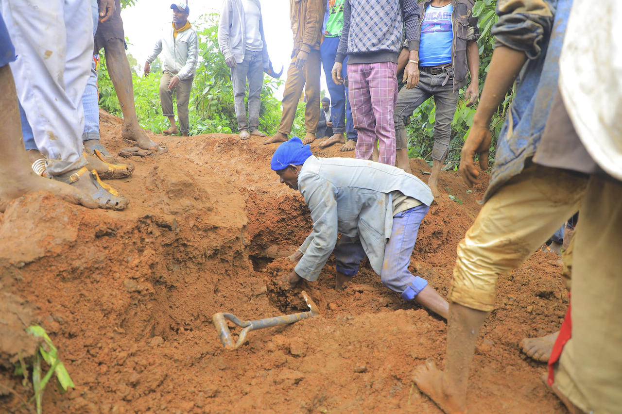 In this handout photo released by Gofa Zone Government Communication Affairs Department, a man searches for survivors hundreds of people gather at the site of a mudslide in the Kencho Shacha Gozdi district, Gofa Zone, southern Ethiopia, Monday, July 22, 2024. (Gofa Zone Government Communication Affairs Department via AP)