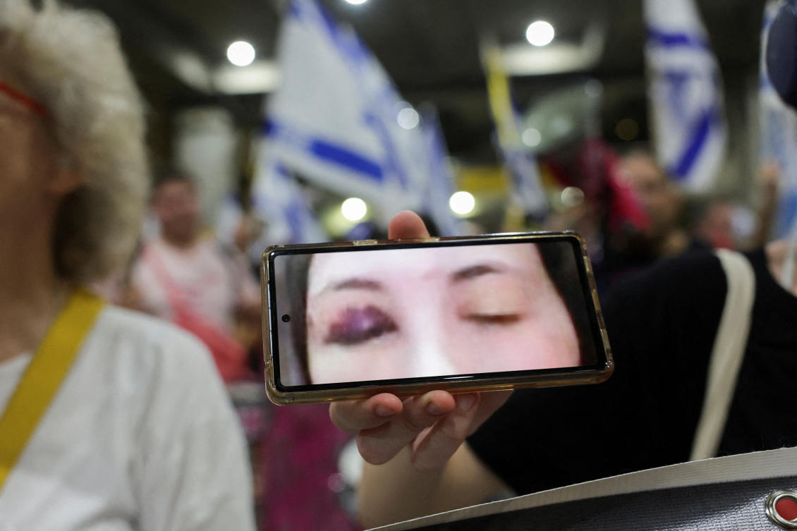 Above, a protester at Ben Gurion International Airport holds a phone displaying an image of Israeli hostage Naama Levy taken during her captivity in Gaza on July 21, 2024. (Reuters)
