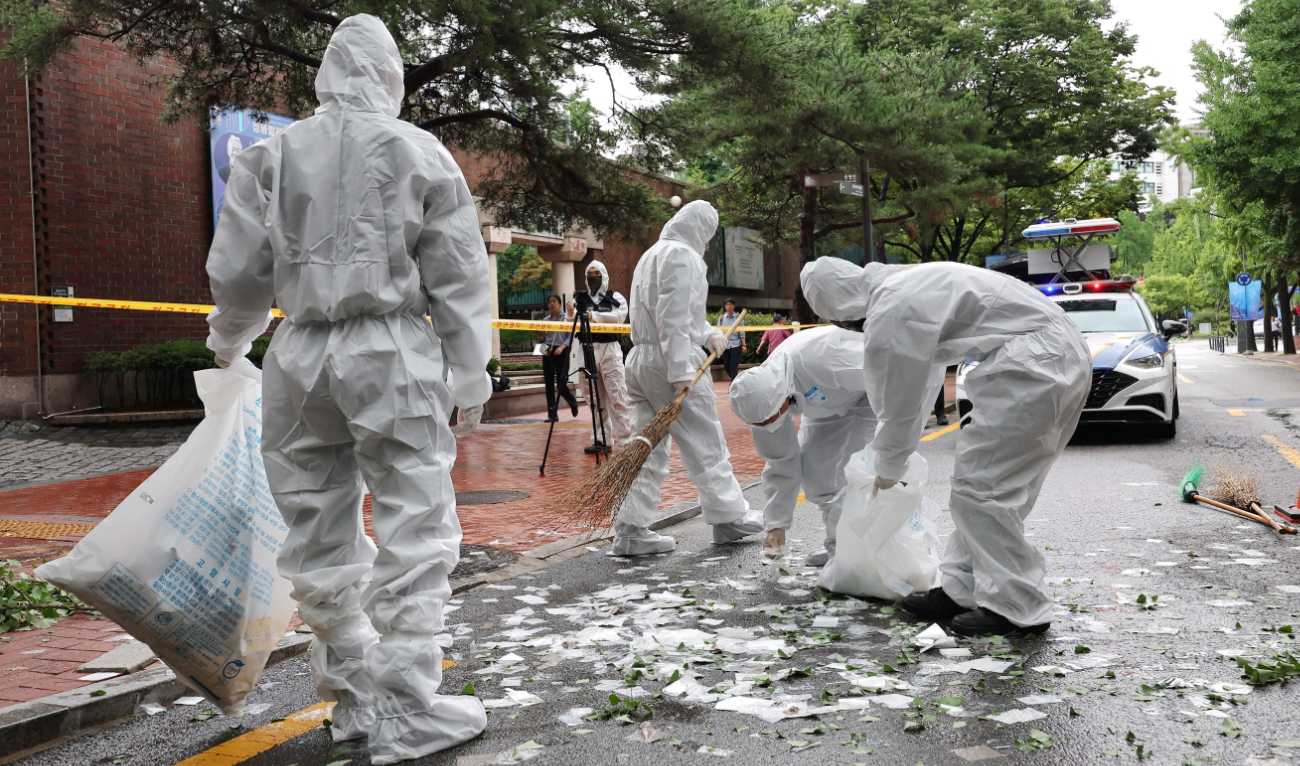 South Korean officials clean up the contents of a trash-carrying balloon sent by North Korea after it landed on a street in Seoul on July 24, 2024. (AFP)