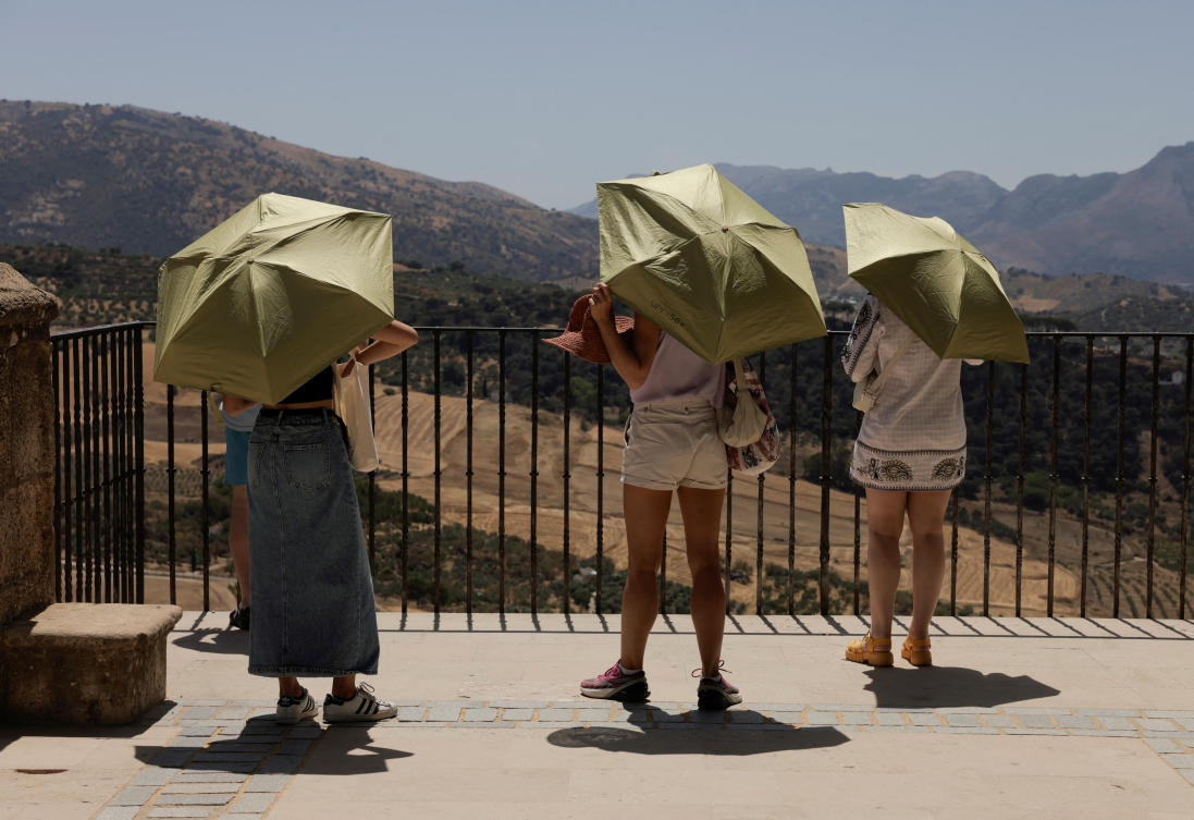 Tourists use umbrellas to protect themselves from the strong midday sun in a park, during a heatwave in Ronda, Spain, on Jul. 24, 2024. (Reuters)