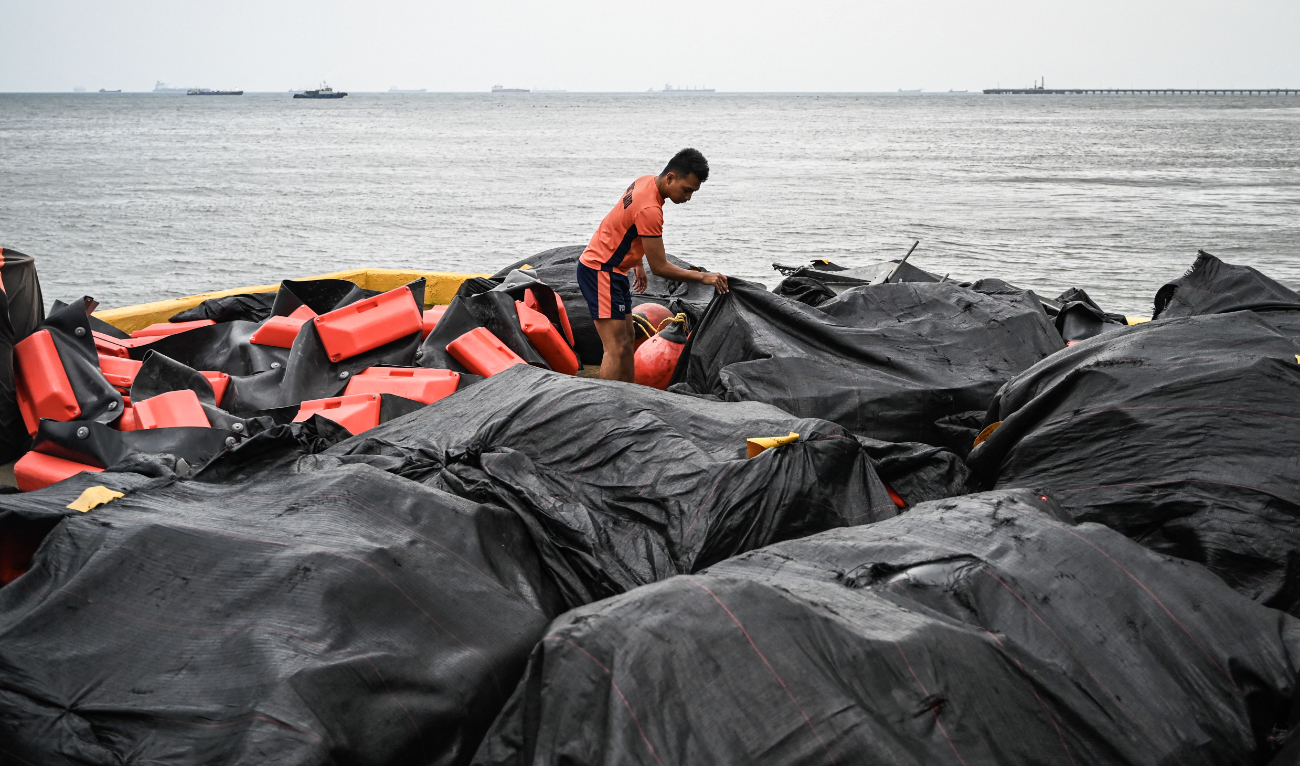 A coast guard personnel arranges an oil spill containment boom to be on standby for deployment at a port in Limay, Bataan on July 25, 2024. (AFP)