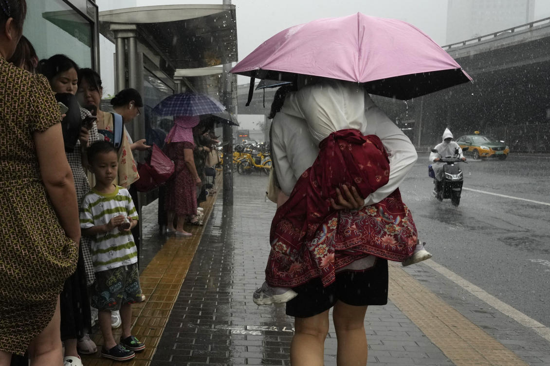 China is enduring a summer of extreme weather, with heavy rains across the east and south coming as much of the north has sweltered under successive heatwaves.Above, a woman carries a child under an umbrella as it rains in Beijing on July 25, 2024. (AP)