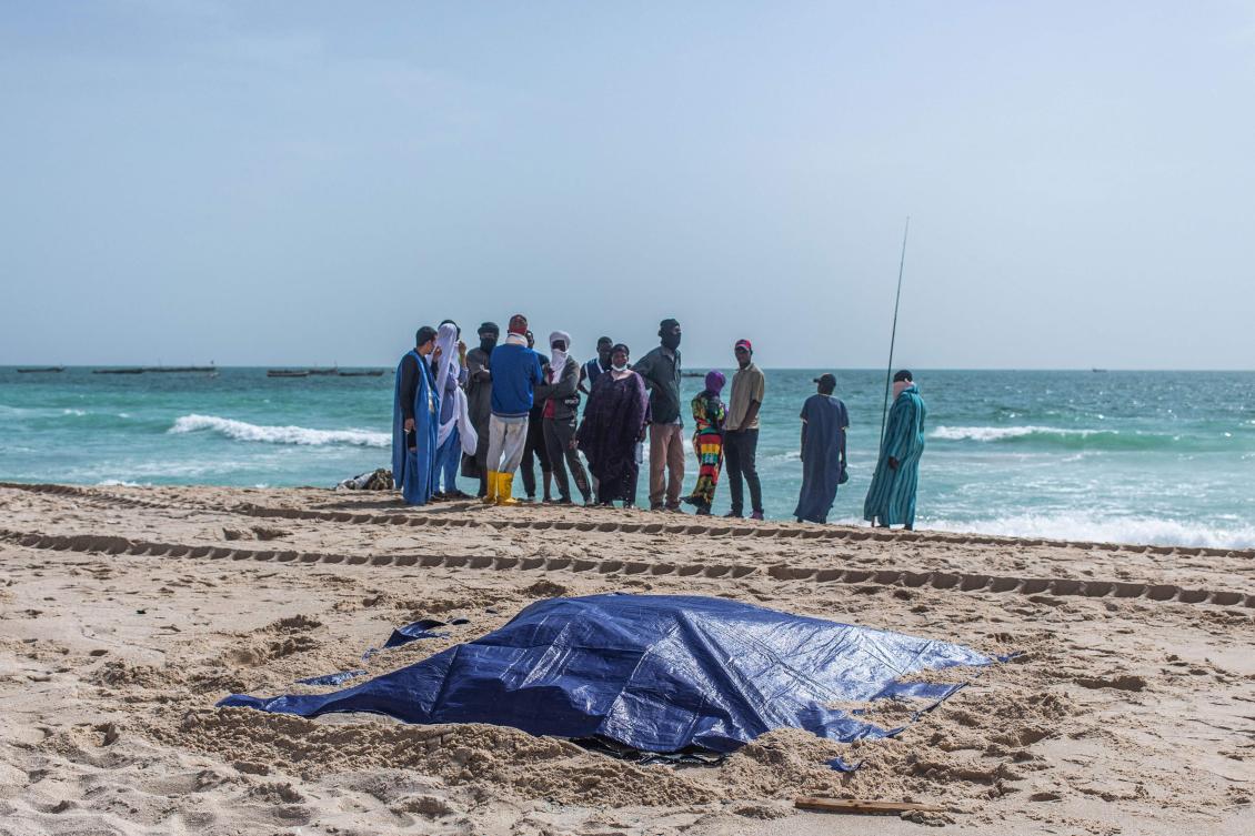 Bystanders look at covered bodies of migrants who perished in a shipwreck off the coast of Mauritania while on a beach outside Nouakchott on July 24, 2024. (AFP)