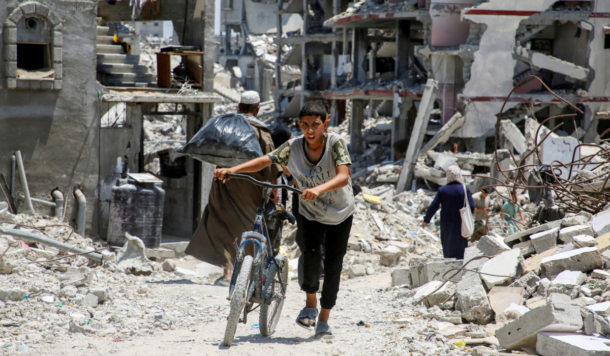 A Palestinian pushes a bicycle as he walks past the rubble of houses destroyed during the Israeli military offensive, amid Israel-Hamas conflict, in Khan Younis in the southern Gaza Strip July 10, 2024. (REUTERS)