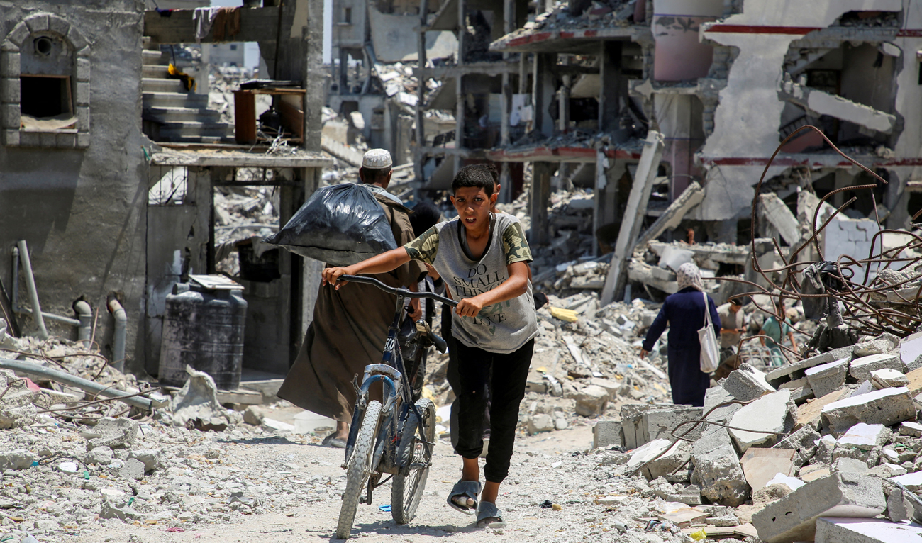 A Palestinian pushes a bicycle as he walks past the rubble of houses destroyed during the Israeli military offensive, amid Israel-Hamas conflict, in Khan Younis in the southern Gaza Strip July 10, 2024. (REUTERS/File)