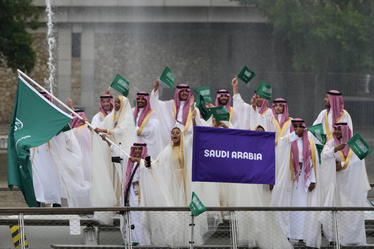 Team Saudi Arabia wave flags on a boat in Paris, France, during the opening ceremony of the 2024 Summer Olympics, Friday, July 26, 2024. (AP Photo/Kirsty Wigglesworth)
