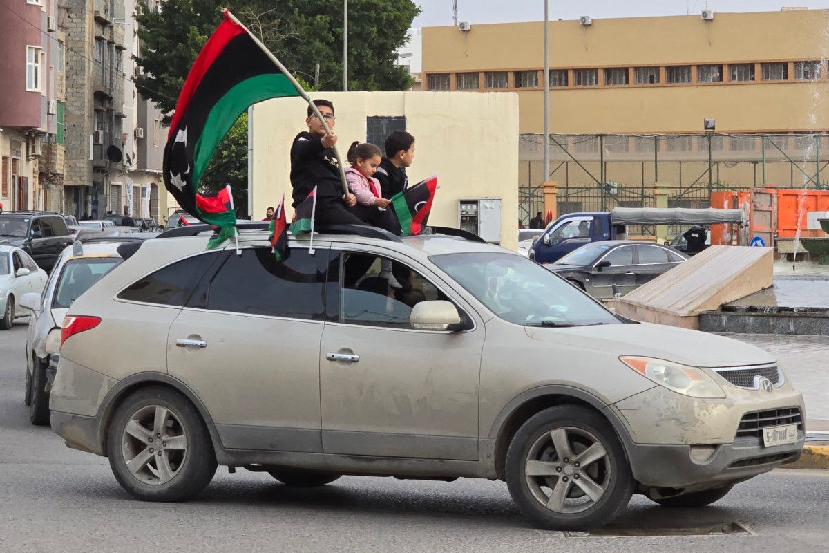 Libyan children sit atop a car with national flags in their hands during celebrations in Tripoli on February 17, 2024, marking the 13th anniversary of the uprising that toppled longtime strongman Muammar Kadhafi. (File/AFP)