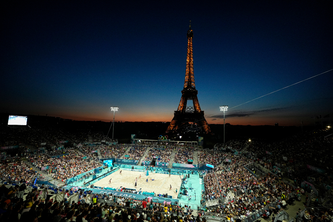 The Eiffel Tower sparkles at dusk as the US, on left, plays Czech Republic in a beach volleyball match at the 2024 Summer Olympics, Sunday in Paris. (AP)