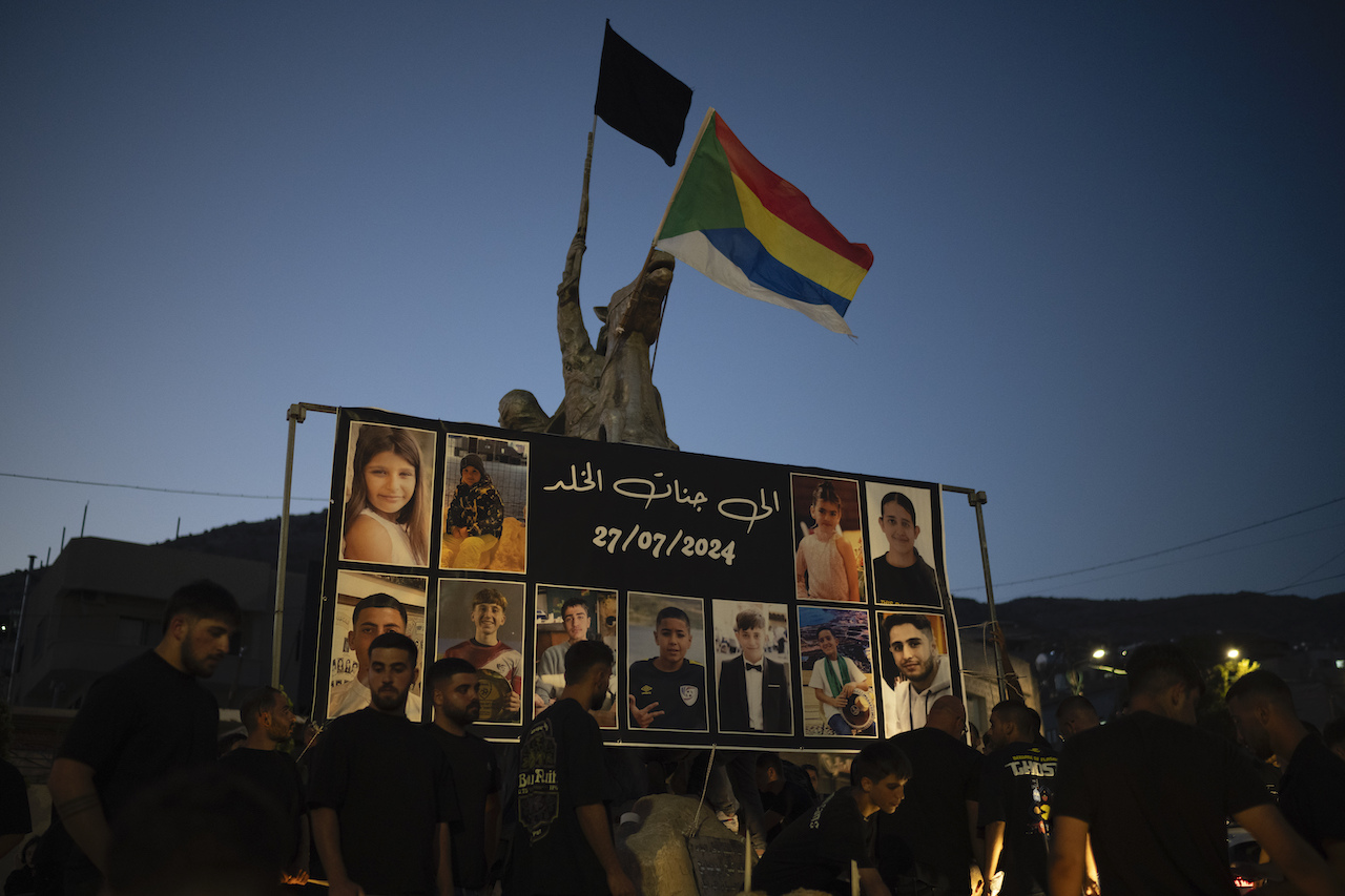 hotos of the children and teens killed in a rocket strike at a football field, are displayed at a roundabout as people light candles in their memories, at the village of Majdal Shams, in the Israeli-annexed Golan Heights, Sunday, July 28, 2024. (AP)