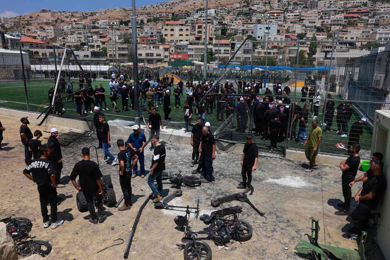Members of the Druze community look at the damaged fence at a football pitch on July 28, 2024 in the Druze town of Majdal Shams in the Israel-annexed Golan Heights. (AFP)
