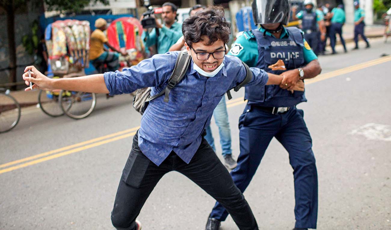A Bangladesh police personnel detains a student during a rally against quotas in government jobs, along a street in Dhaka on July 29, 2024. (AFP)