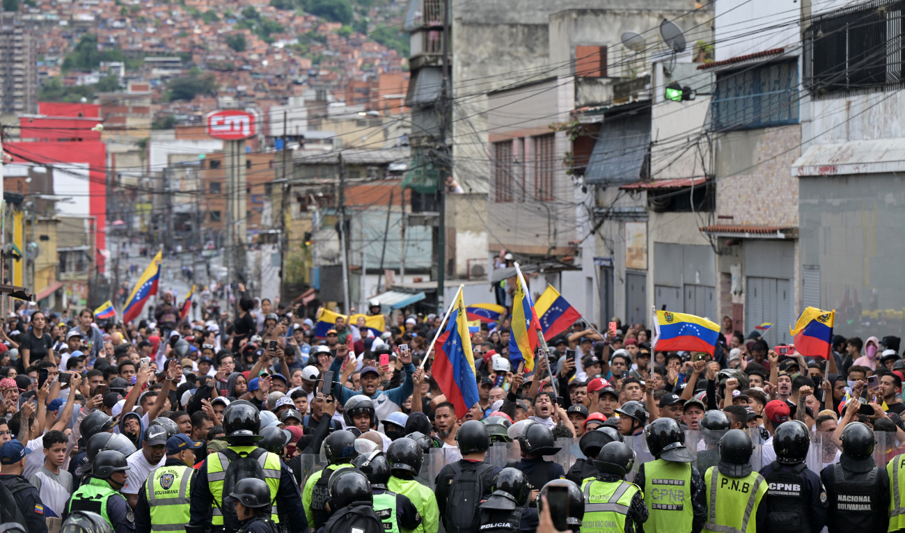 Opponents of Venezuelan President Nicolas Maduro's government protest in front of members of the Bolivarian National Police in the Catia neighborhood of Caracas on July 29, 2024, a day after the Venezuelan presidential election. (AFP)