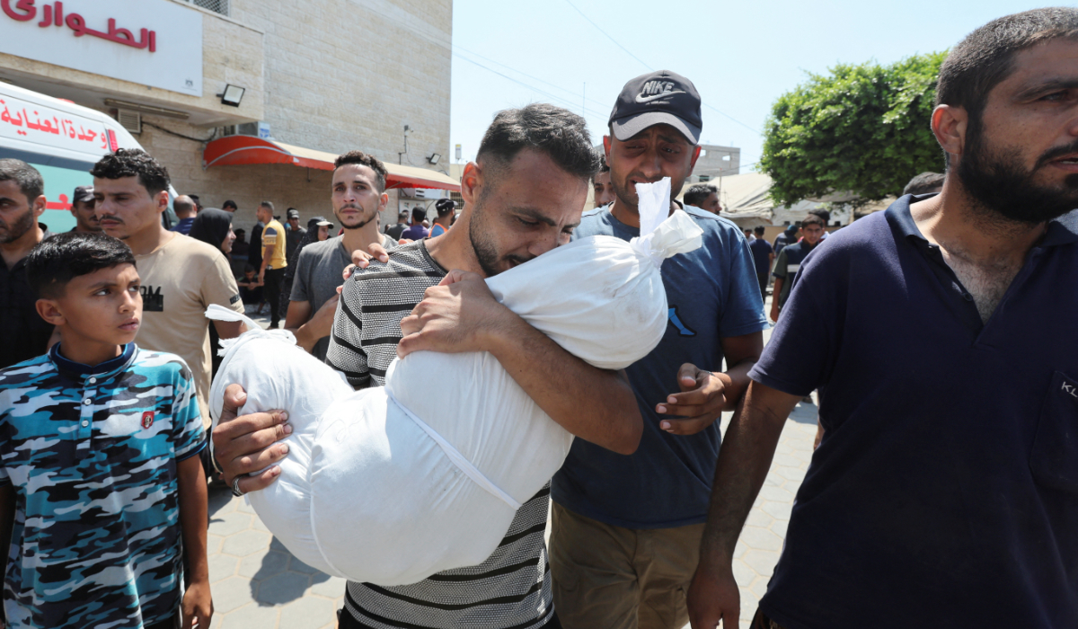 A Palestinian man carries a body following an Israeli strike, amid the Israel-Hamas conflict, at Al-Aqsa Martyrs Hospital in Deir Al-Balah in the central Gaza Strip, July 27, 2024. (REUTERS)