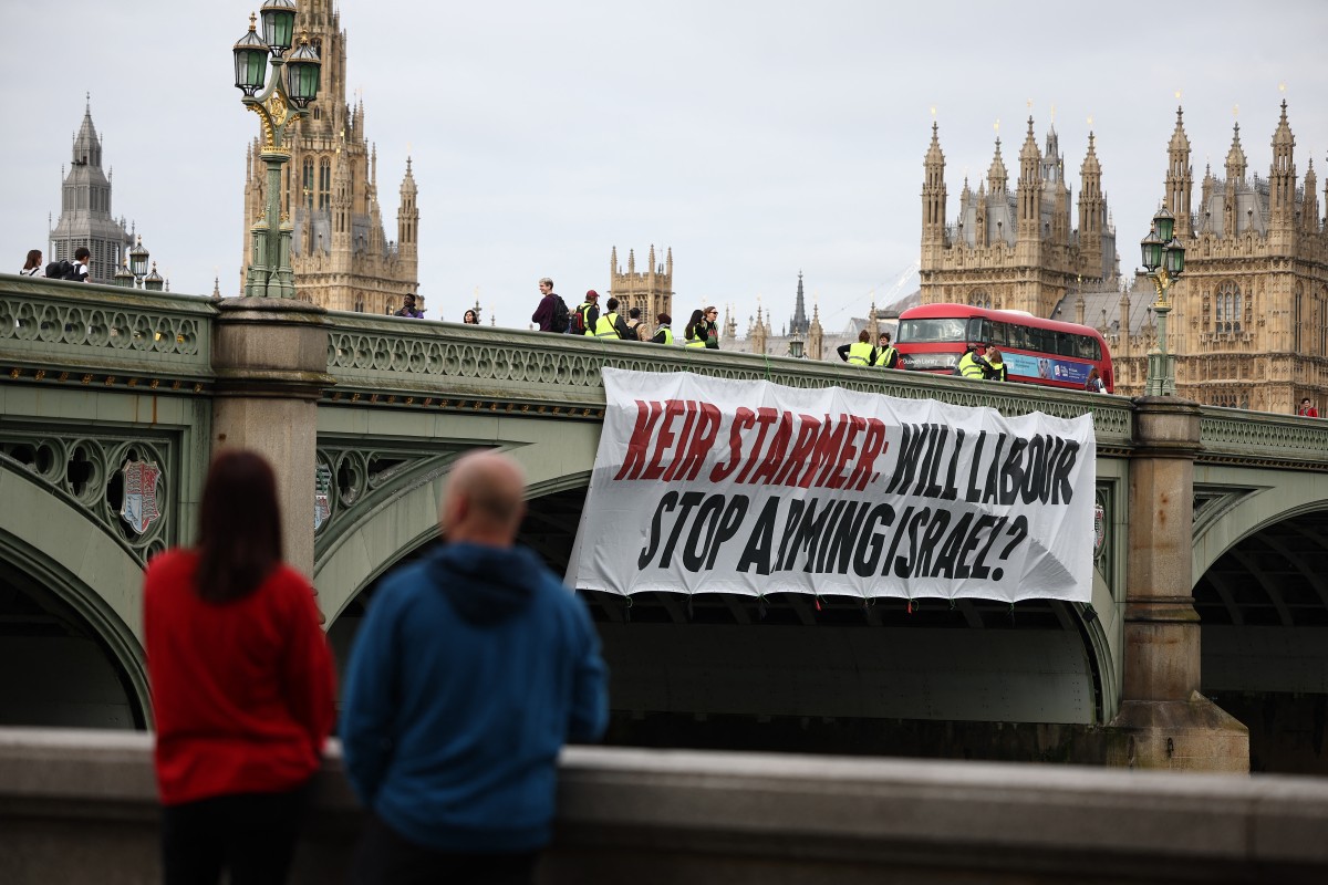 A banner reading "Keir Starmer: Will Labour Stop Arming Israel?" is hung over the side of Westminster Bridge, in front of the Palace of Westminster, home to the Houses of Parliament, during early morning rush hour in London on June 3, 2024. (File/AFP)