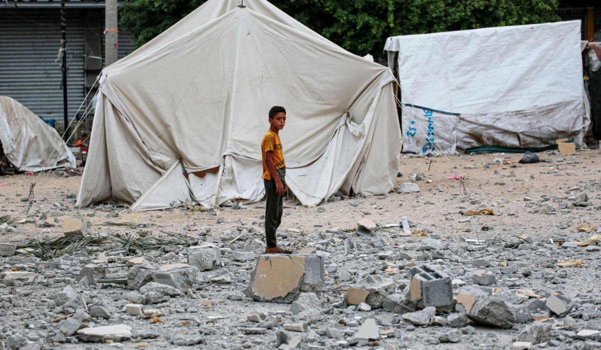 A Palestinian youth stands on rubble close to tents housing internally displaced people, erected in the square near the Deir al-Balah municipality building, destroyed following Israeli bombardment of Deir al-Balah, in the central Gaza Strip on June 28, 2024, amid the ongoing conflict between Israel and the Palestinian Hamas militant group. (AFP)