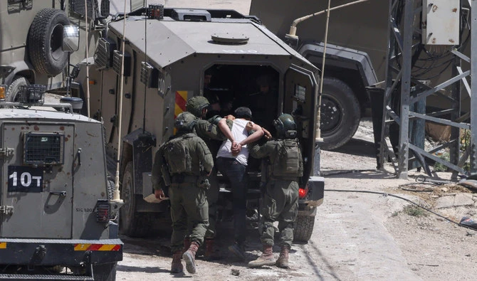 Israeli soldiers detain a Palestinian man during a raid in the occupied West Bank town of Deir Al-Ghusun near Tulkarem in May 2024. (AFP/File)