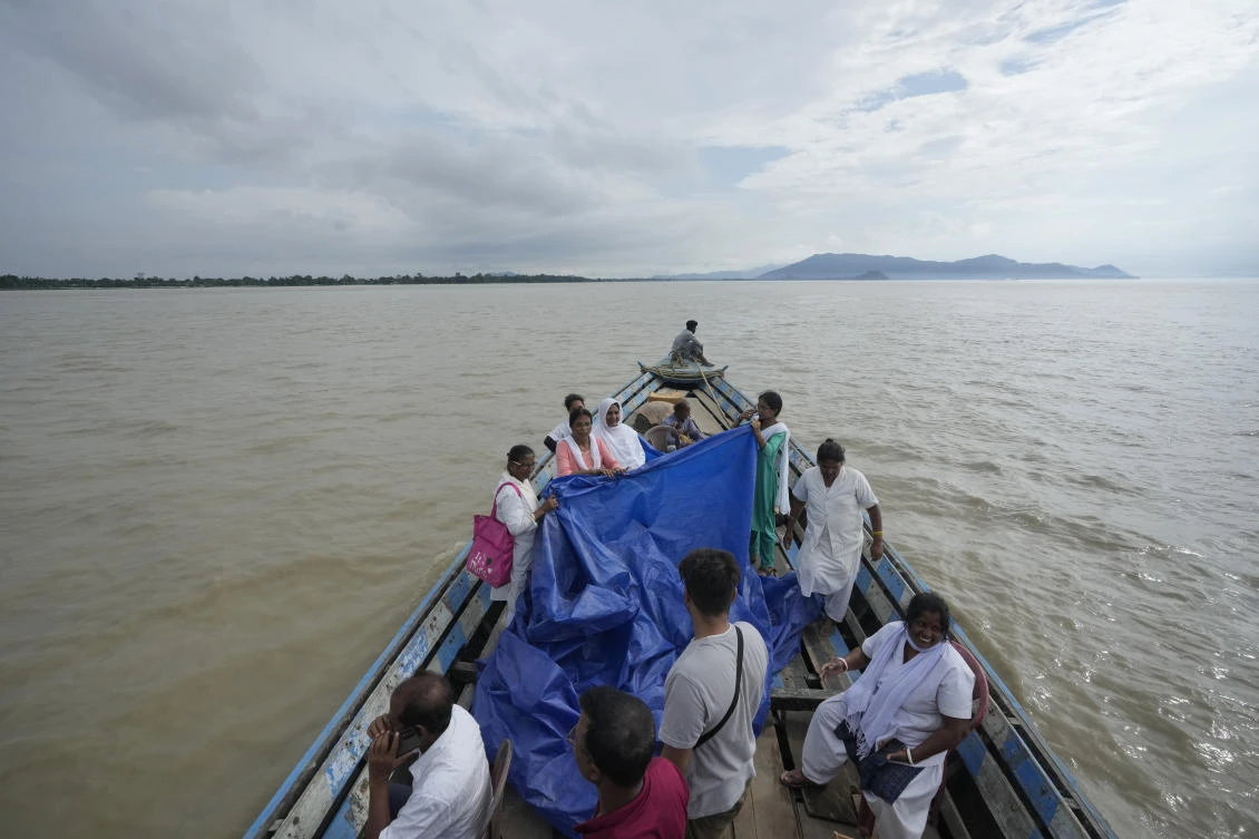 Health officers hold up a tarpaulin to cover 25-year-old Jahanara Khatoon as she delivers a baby on a boat over the River Brahmaputra, in the northeastern Indian state of Assam, on Jul. 3, 2024. (AP)