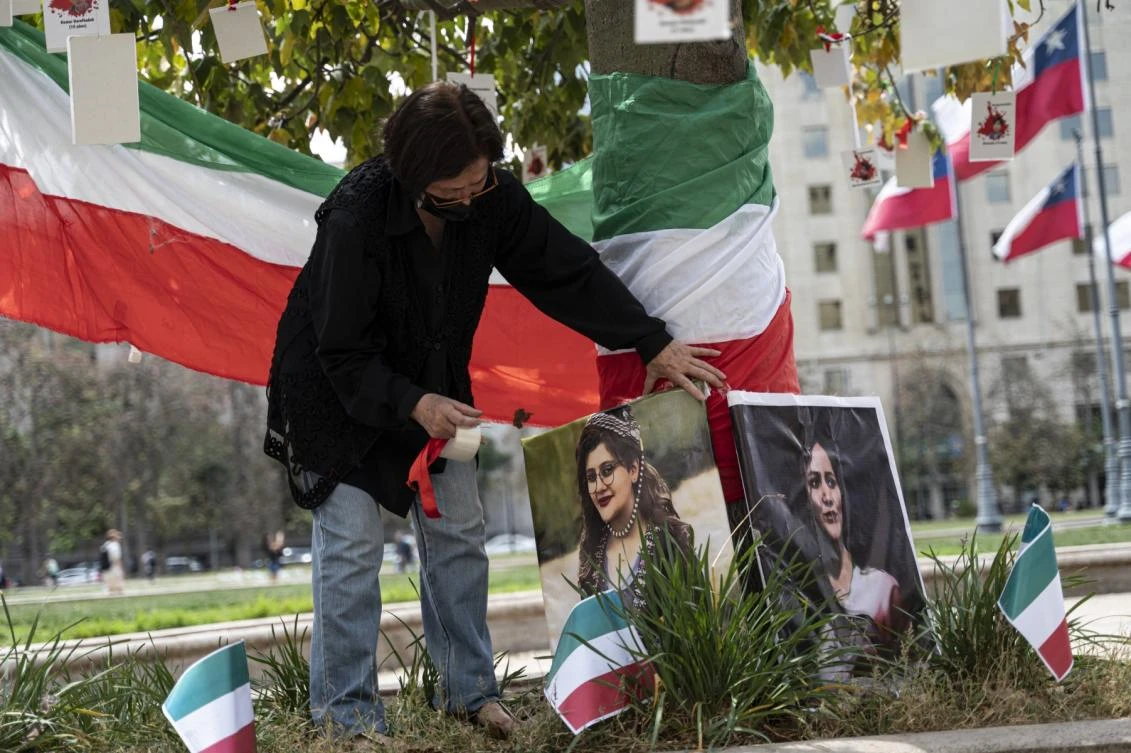 A woman places photographs of Kurdish woman Mahsa Amini on a tree in front of the Palacio de la Moneda as Iranians living in Chile protest against violence against women in their country. (AFP)