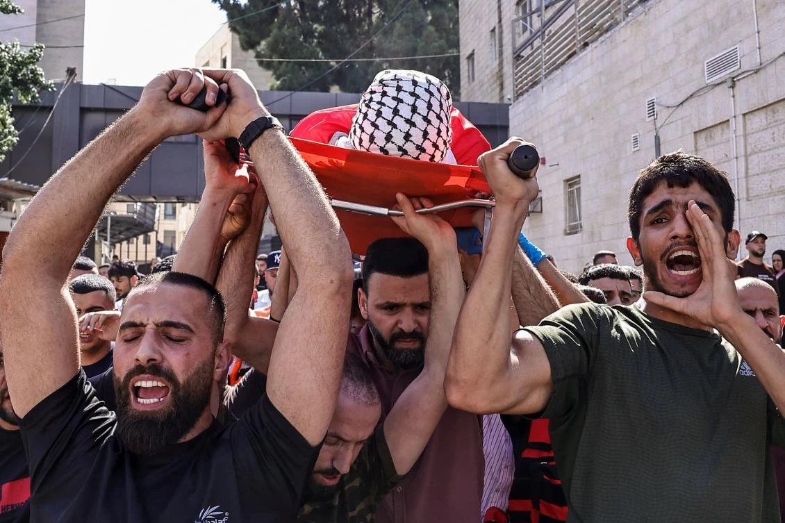Mourners carry the body of Ghassan Ghareeb, who was killed during an Israeli raid in the occupied West Bank, during his funeral in Ramallah on July 9, 2024. (AFP)