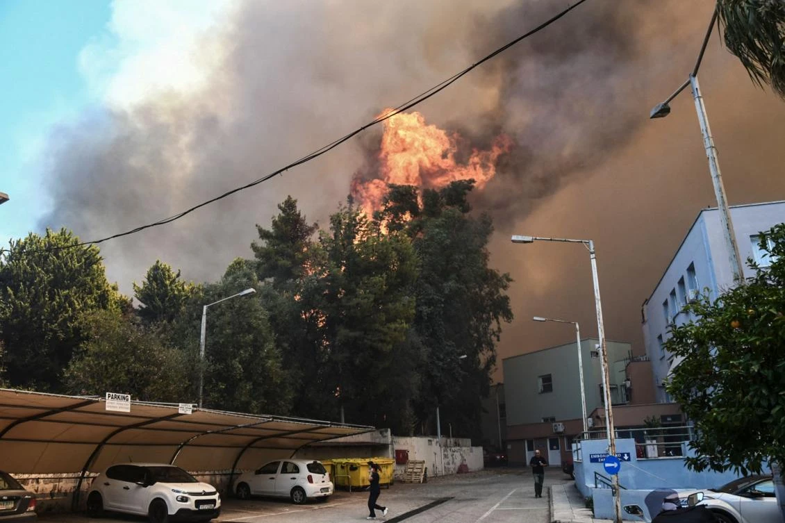 Bystanders flee as a wildfire burns next to a hospital near Patras on Jul. 9, 2024. (AFP)