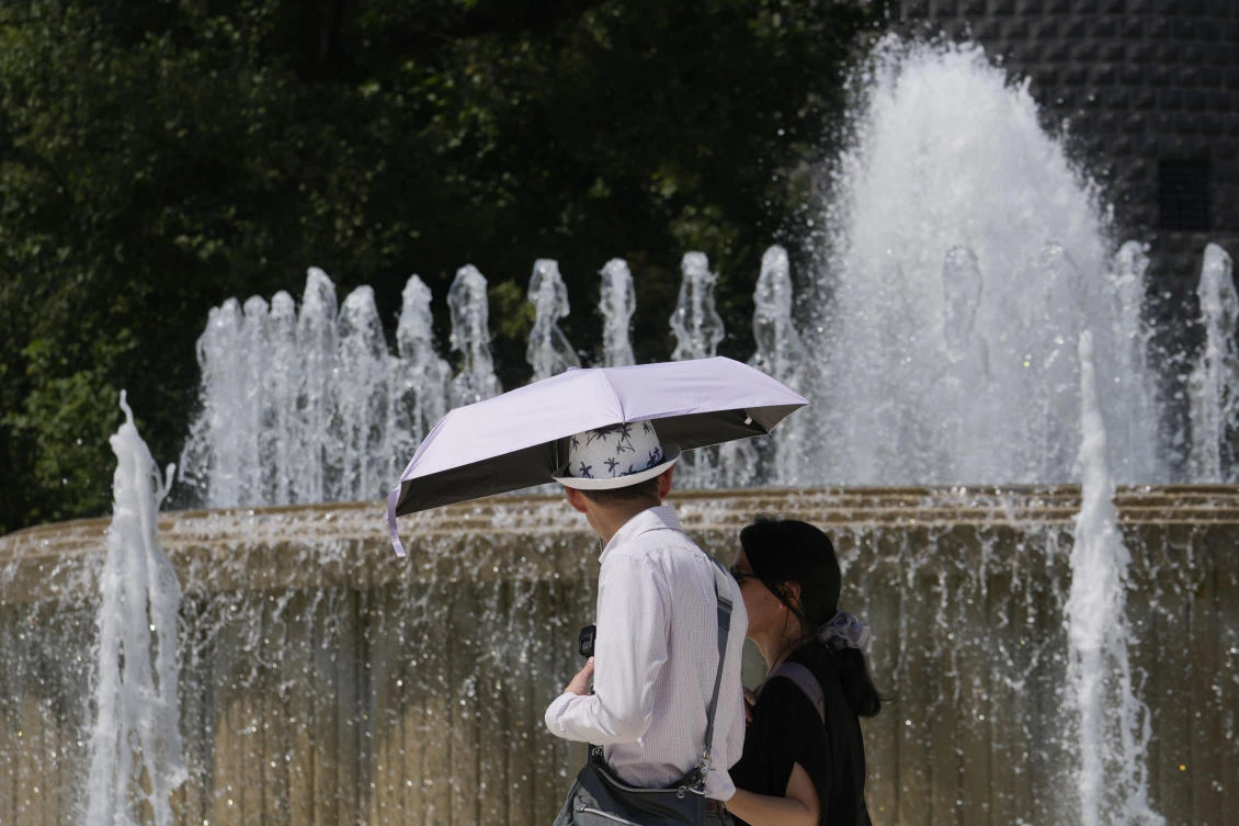 Tourists shelter from the sun as they pass by a fountain in front of the Sforzesco Castle in Milan on July 11, 2024. (AP)