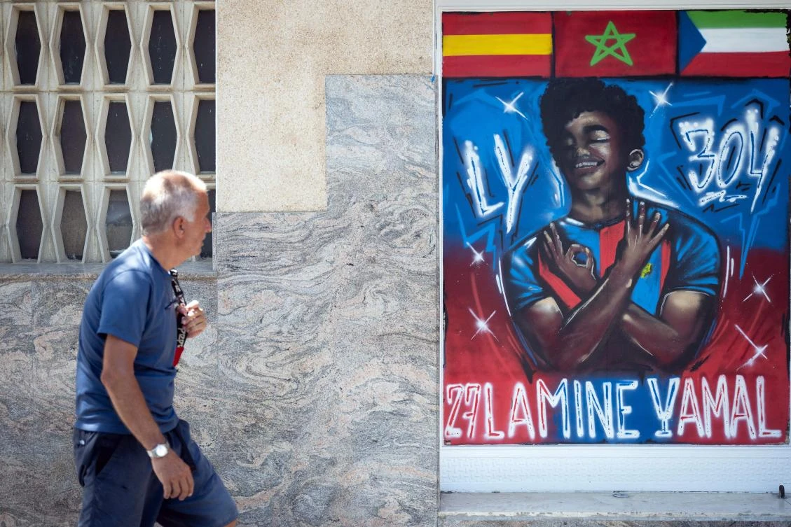 A man walks past a graffiti depicting Lamine Yamal in Rocafonda, the neighborhood where Spain’s forward grew up, in Mataro, 35km from Barcelona, on July 11, 2024. Every time he scores a goal, Lamine Yamal usually signs the number 304 with his hands. It is the postal code of the humble Catalan neighborhood where he spent part of his childhood, Rocafonda, which is now very excited about his success and for finally being in the news for good reasons. (AFP)