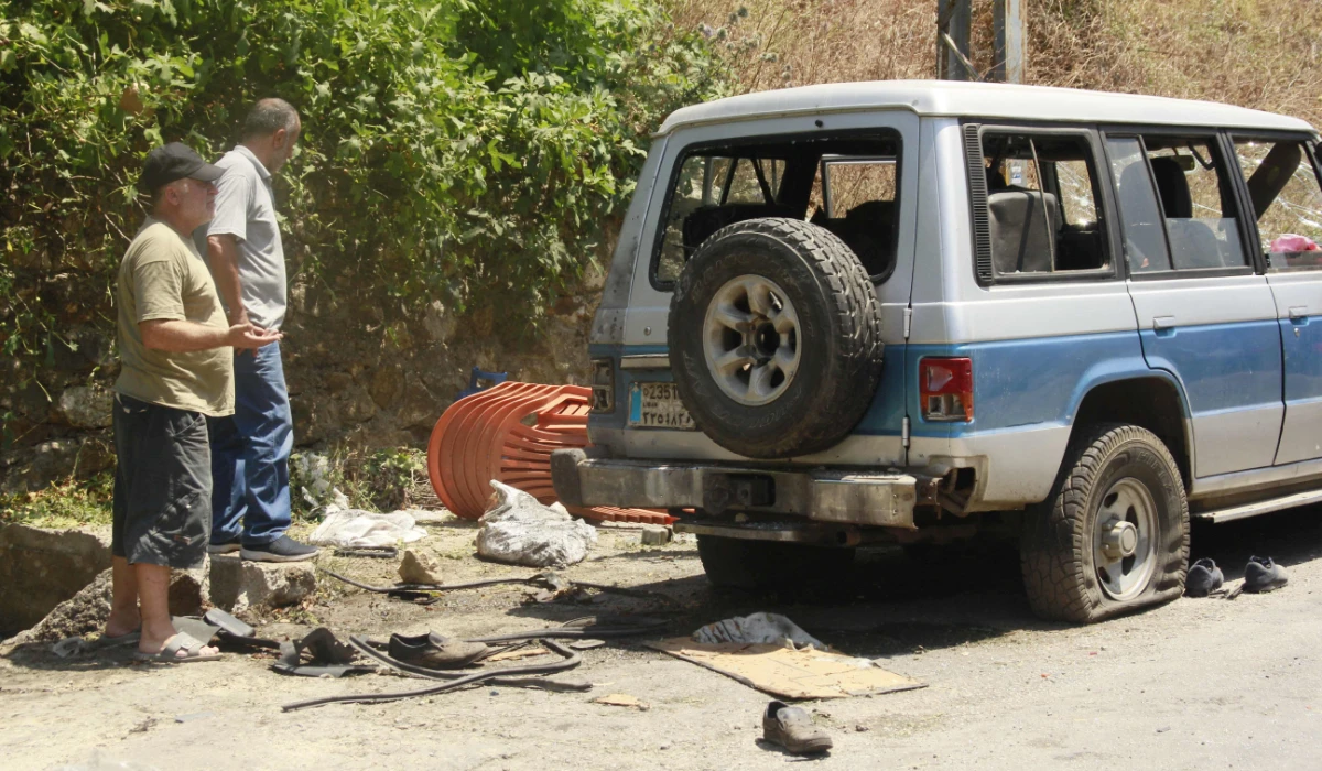 Two Lebanese men inspect a damaged vehicle following an Israeli strike along the road between Khardali and Marjeyoun, near the village of Deir Mimas, close to the southern Lebanese border with Israel on July 13, 2024, amid ongoing cross-border clashes between Israeli troops and Hezbollah fighters. (AFP)