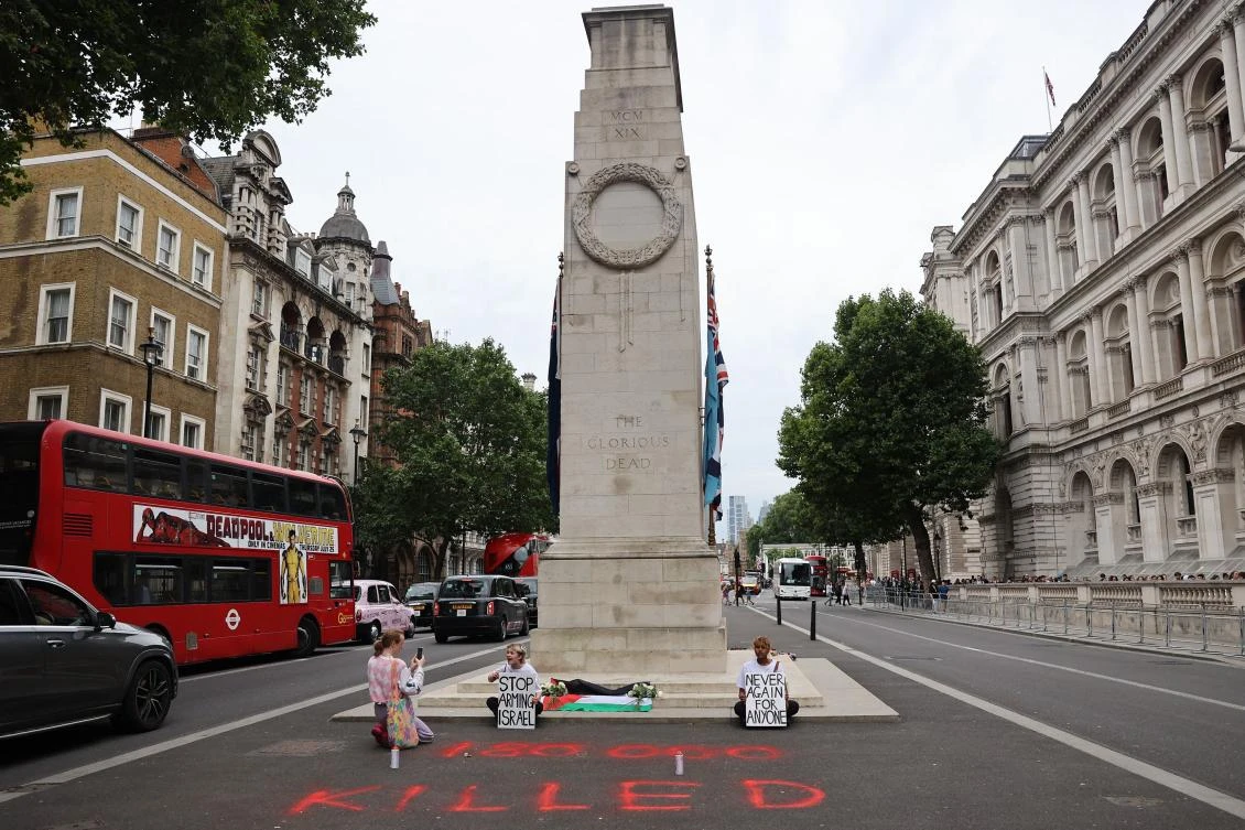 Youth Demand activists hold placards reading “Stop arming Israel” and “Never again for anyone” after laying flowers and a Plaestinian flag at the Cenotaph war memorial in central London on July 15, 2024 during a protest to “commemorate the thousands killed in Israel’s genocidal assault on Gaza.” (AFP)
