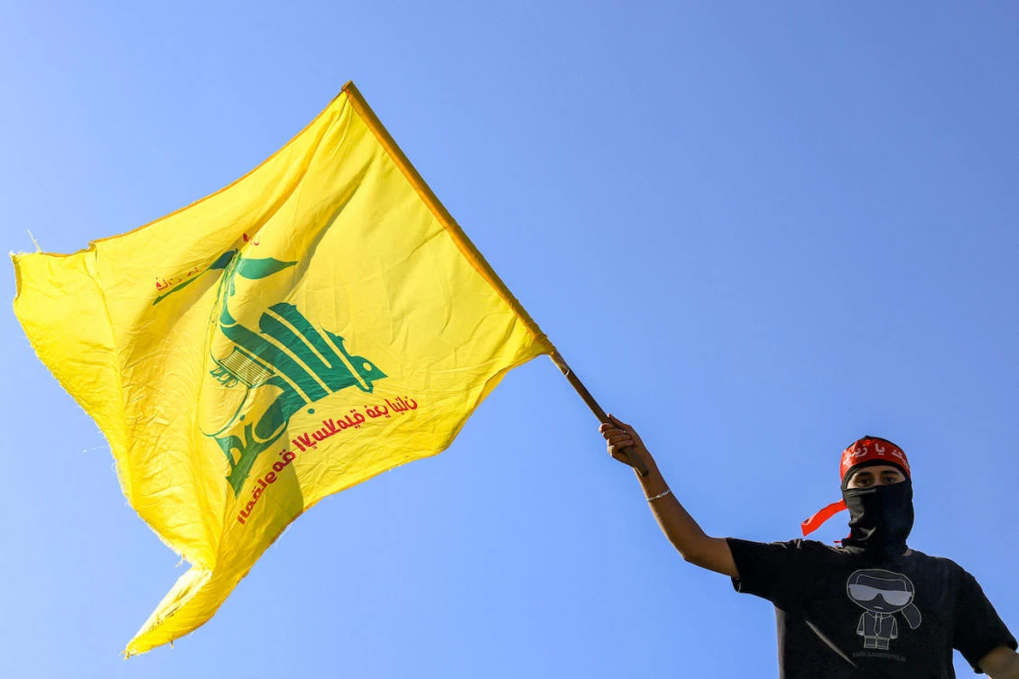 A masked demonstrator waves a Hezbollah flag during a demonstration supporting the Palestinians in Beirut. (File/AFP)