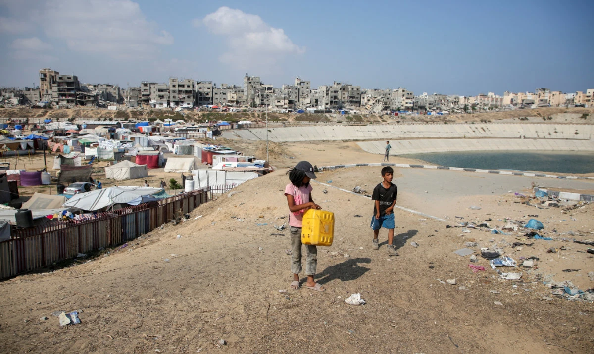 Palestinian children walk near a wastewater pool as displaced Palestinians shelter in a tent camp, amid the Israel-Hamas conflict, in Khan Younis in the southern Gaza Strip, July 15, 2024. (Reuters)