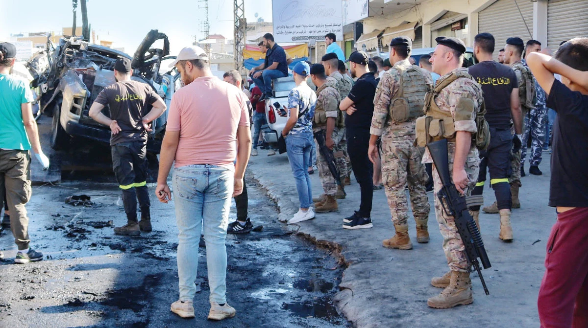 Residents and soldiers check the wreckage of a car in which a militant leader from a group close to Hamas was killed by an Israeli strike in the Bekaa region of eastern Lebanon on Thursday. (AFP)
