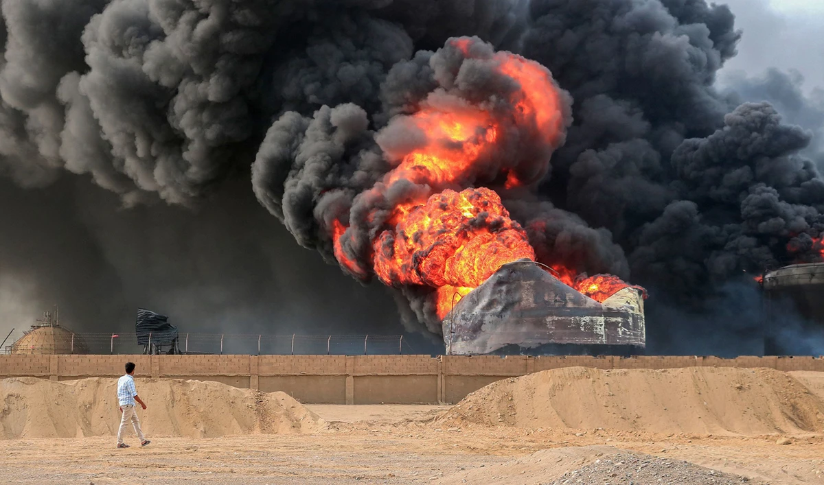 A man walks across from a raging fire at oil storage tanks a day after Israeli strikes on the port of Yemen’s Houthi-held city of Hodeida on July 21, 2024. Yemen’s Houthi rebels on July 21 promised a “huge” retaliation against Israel following a deadly strike on the port of Hodeida, as regional fallout widens from months of war in Gaza. (AFP)