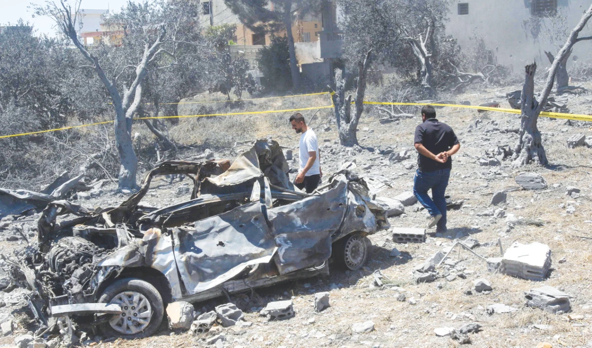 Residents check a destroyed vehicle in the aftermath of an Israeli airstrike near Lebanon’s southern village of Jmaijmeh amid ongoing cross-border clashes. (AFP)