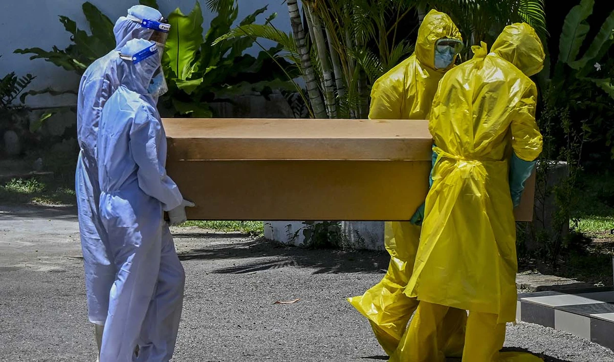 Workers carry a cardboard coffin of a Covid-19 coronavirus victim for cremation at a cemetery in Colombo on August 31, 2021. (AFP/File)