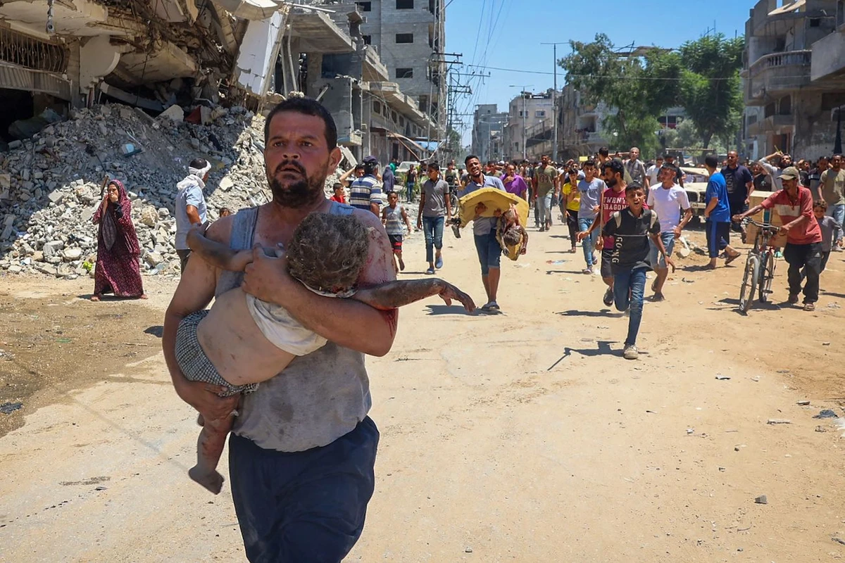 People carry children injured during Israeli bombardment as people flee at the Al-Bureij refugee camp in the central Gaza Strip on July 23, 2024. (AFP)