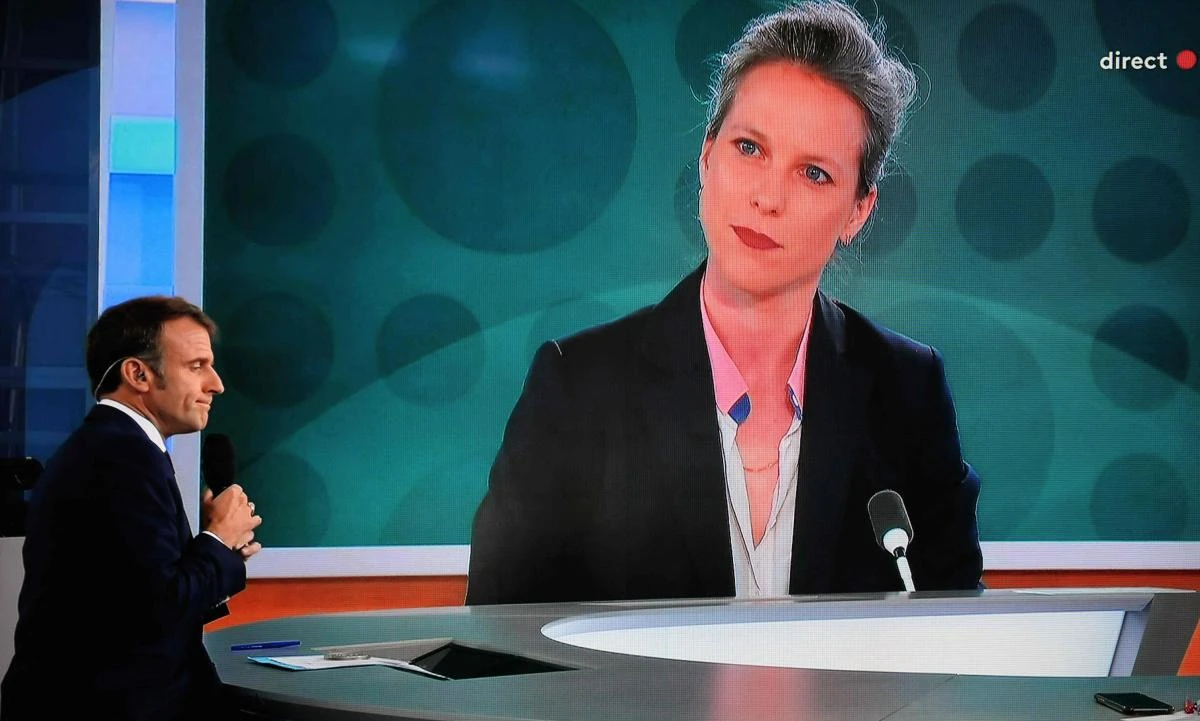 This photograph shows a television screen broadcasting France’s President Emmanuel Macron addressing a live interview as a portrait of Lucie Castets, the ‘Nouveau Front Populaire’ choice for Prime Minister, is displayed on a giant screen, on French TV channel France 2, on July 23, 2024. (AFP)