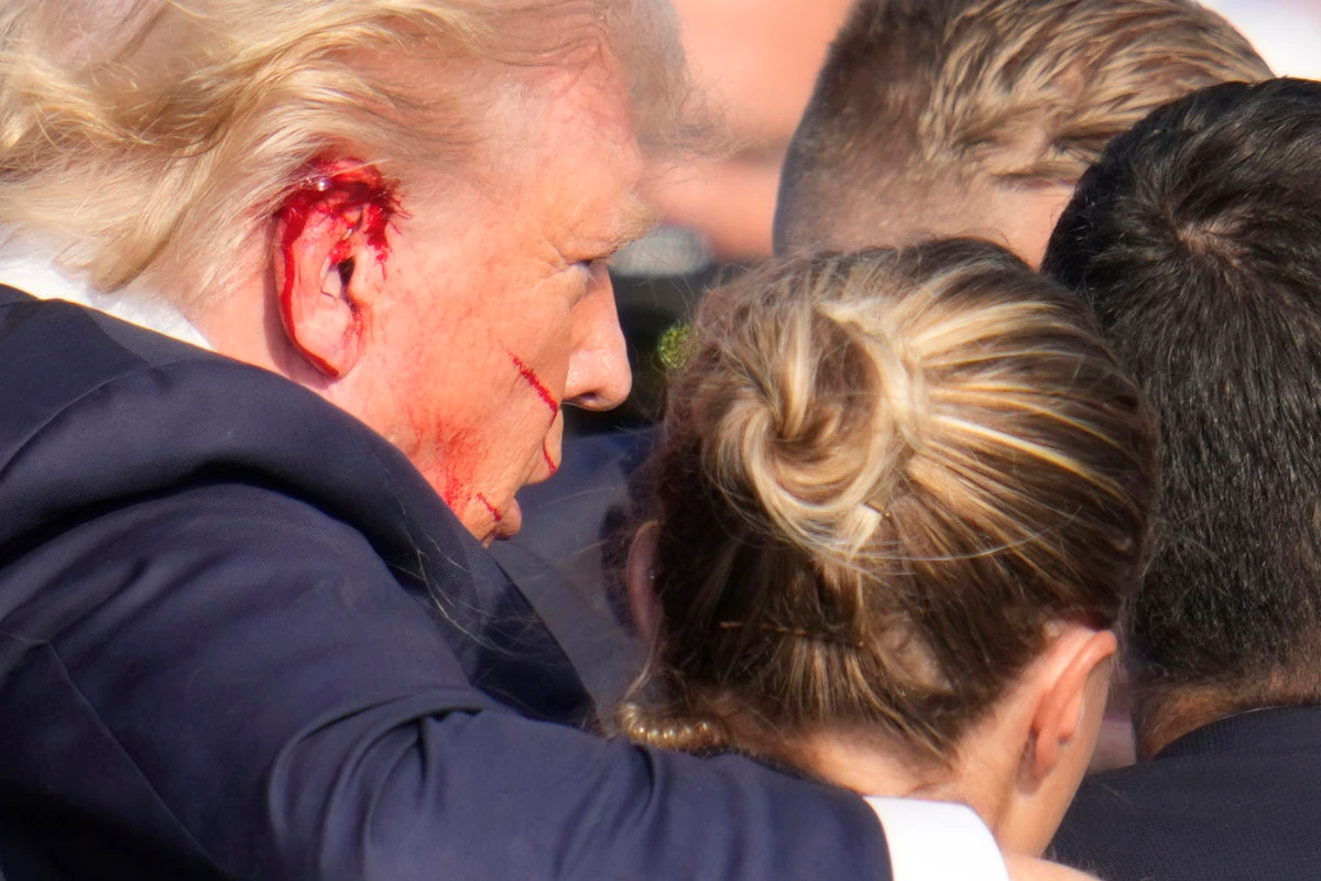 Republican presidential candidate Donald Trump, his ear splattered with blood, is helped off the stage by US Secret Service agents after a 20-year-old assassin fired at him during a campaign rally in Butler, Pennsylvania, on July 13, 2024. (AP Photo/File)
