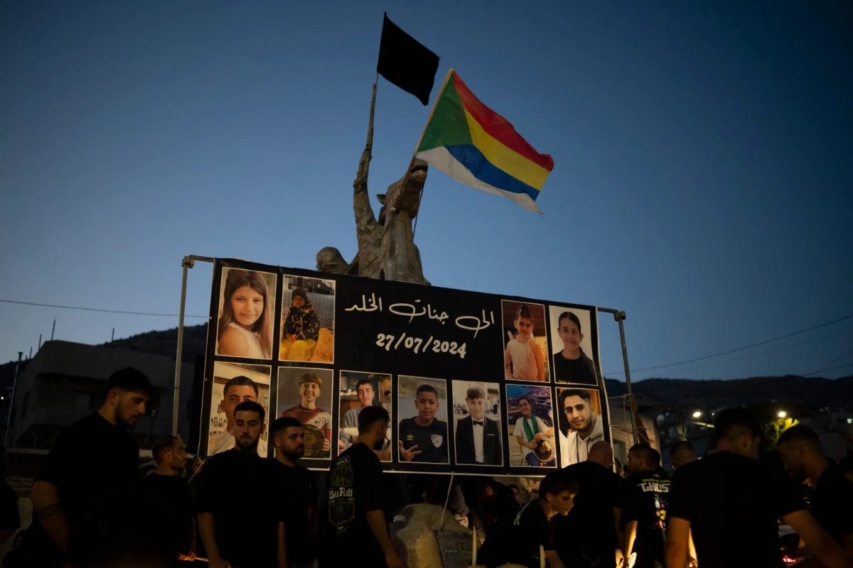 Photos of the children and teens killed in a rocket strike at a soccer field, are displayed at a roundabout as people light candles in their memories, at the village of Majdal Shams, in the Israeli-annexed Golan Heights, on July 28, 2024. (AP)