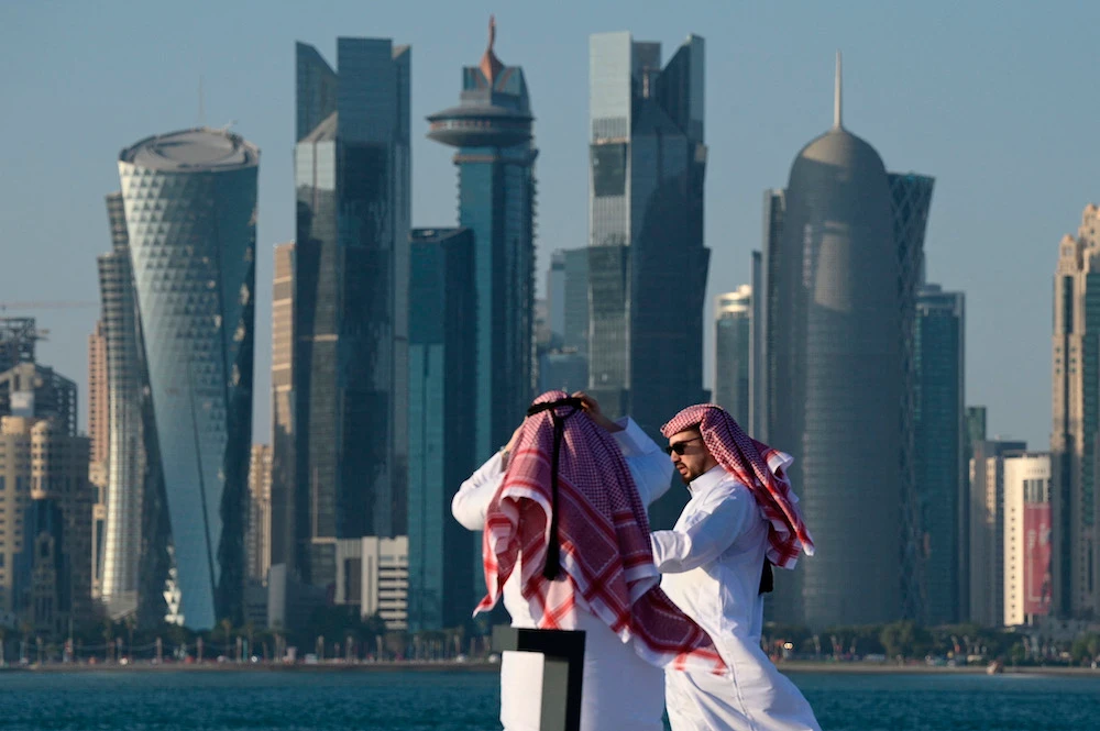 Two men walk along the Corniche promenade as Doha’s skyline is seen in the background. File/AFP
